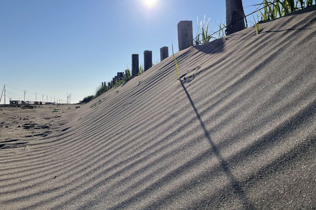 Polarized sunglasses resting on light sand near the shore