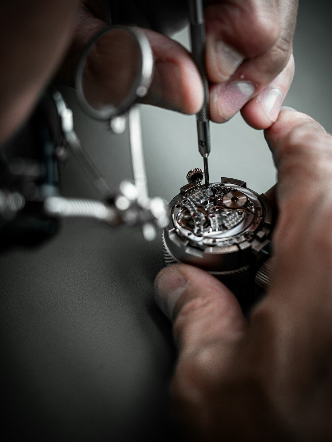 Close-up of hands assembling a mechanical watch with fine tools
